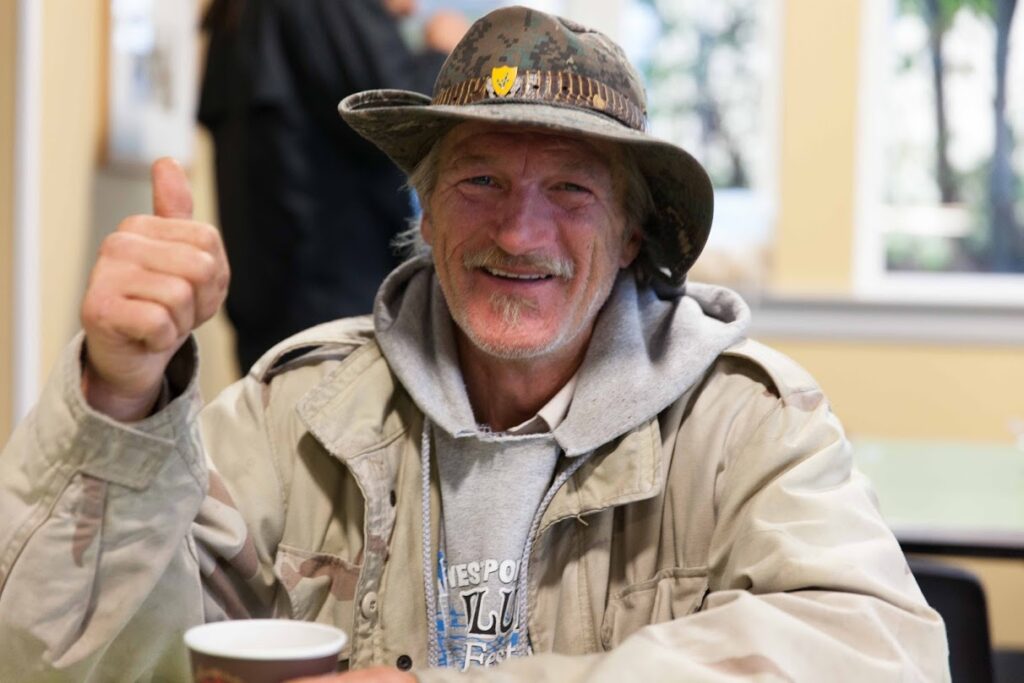 Elderly man with hat holds up keys